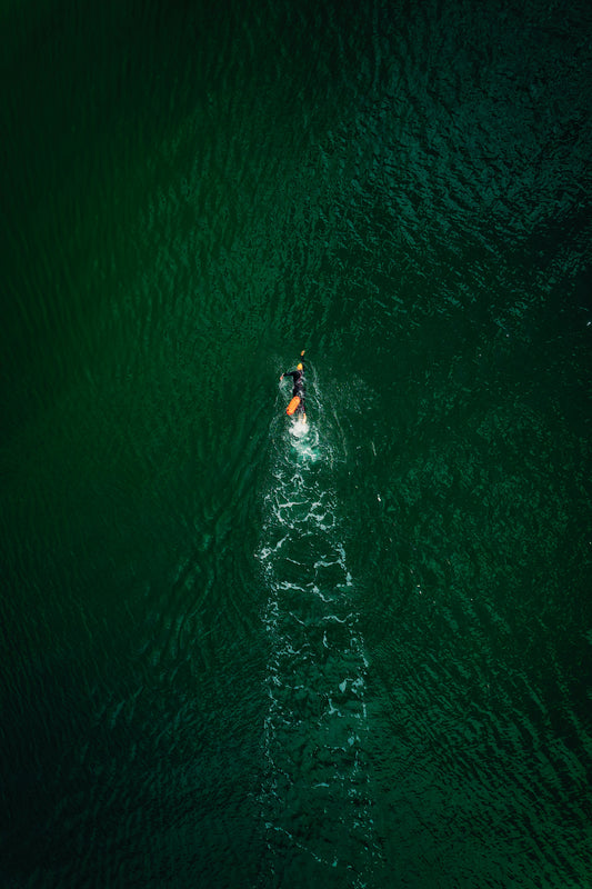 Triathlete swimming in open water with a safety buoy in tow